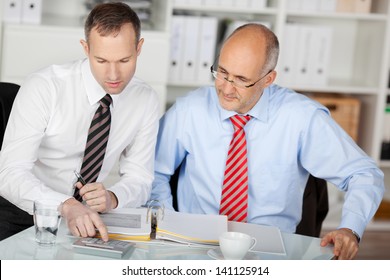 Two businesspersons discussing using laptop in the office