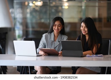 Two businesswoman working on tablet computer and discussing business data at modern office.