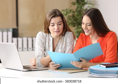 Two businesswomen consulting a report together on a desk at office