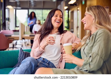 Two Businesswomen Having Informal Meeting In Breakout Seating Area Of Modern Office