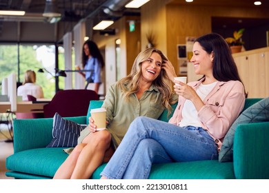 Two Businesswomen Having Informal Meeting In Breakout Seating Area Of Modern Office