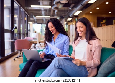 Two Businesswomen Having Informal Meeting In Breakout Seating Area Of Modern Office