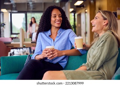 Two Businesswomen Having Informal Meeting In Breakout Seating Area Of Modern Office