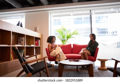 Two Businesswomen Having Socially Distanced Meeting Sitting On Office Sofa During Health Pandemic