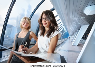 Two businesswomen looking into papers in futuristic interior - Powered by Shutterstock