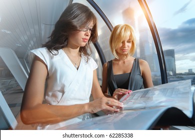 Two businesswomen looking into papers in futuristic interior - Powered by Shutterstock