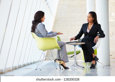 Two Businesswomen Meeting Around Table In Modern Office