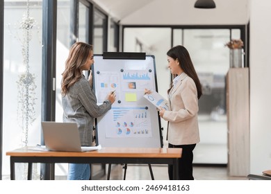 Two Businesswomen presenting financial reports on whiteboard - Powered by Shutterstock