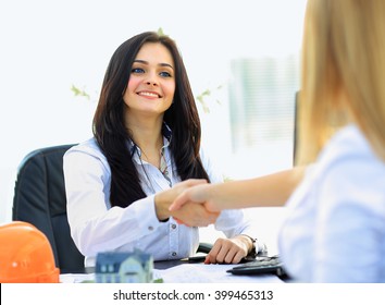 Two businesswomen shaking hands in modern office