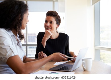 Two Businesswomen Using Laptop Computer In Office Meeting