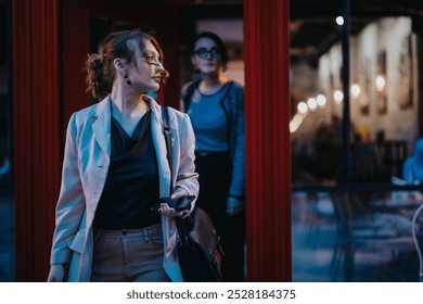 Two businesswomen walking out of a building at night in an urban city street after work. Professional women in business attire. - Powered by Shutterstock