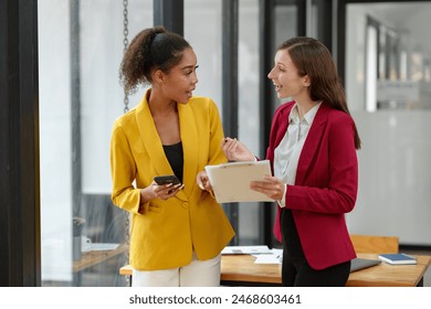 Two businesswomen working together using documents Work files talk about business projects. Creative team of African American female executives stand meeting in modern office. - Powered by Shutterstock