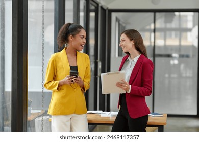 Two businesswomen working together using documents Work files talk about business projects. Creative team of African American female executives stand meeting in modern office. - Powered by Shutterstock