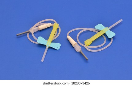 Two Butterfly Intravenous Cannula Used For Blood Sample Collection And Intra Venous Medication Administration.image Isolated On A Blue Background 