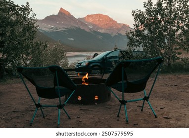 two camp chairs in front of a fire pit with mountains in the background in smmer - Powered by Shutterstock