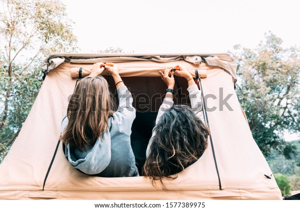 Two\
camper girls who love nature set up their tent from inside. How to\
set up a tent is not always an easy task. Camping experience is an\
advantage. Horizontal picture. Blank space to\
type.