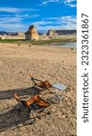 Two camping chairs and one table set up at Lone Rock Beach campground with scenic view of Wahweap Bay at Lake Powell, Glen Canyon Recreation Area, Page, Utah, USA. Van life and road trip in summer