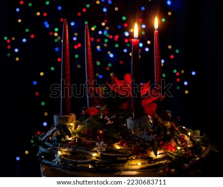 Two candles glow on Advent Wreath. Lighting the second candle on the second Sunday in December. Beautiful red Poinsettia, Christmas Star flower. Festive Christmas red and golden holiday background. 