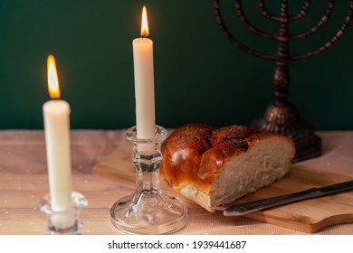 two candles, a menorah and Homemade challah on a wooden table.