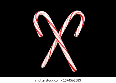 Two Candy Canes Crossed On An Isolated Black Background