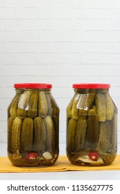 Two cans of pickled cucumbers are located on a white background. Harvest for the winter. Vertical photo. Free place for the inscription.