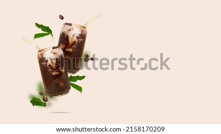 Two can-shaped glass with iced coffee, coffee beans and leaves in the air. Flying Cold coffee with non-dairy milk. Modern and creative composition of flying summer vegeterian drink copy space. Stock photo © 