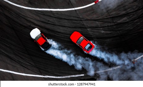 Two car drifting battle on asphalt street road race track with smoke, Aerial view automobile and automotive modify tuning car competition battle with black tire skid mark texture and background.