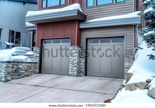 Two car garage with glass paned gray doors at the\
facade of home in winter