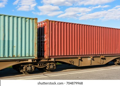 Two cargo containers on a flat car train parked in a shipping yard.