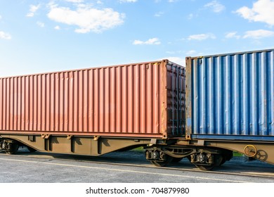 Two cargo containers on a flat car train parked in a shipping yard.