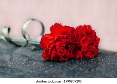 Two Carnations Lie On A Marble Tombstone.