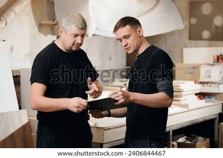 Two carpenters man are discussing project for making wood furniture in workshop. Workplace industry small Business concept.