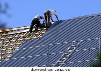 Two carpenters are replacing roof tiles in Norway. - Shutterstock ID 2161207183