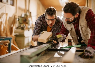 Two carpenters working together in a woodworking shop