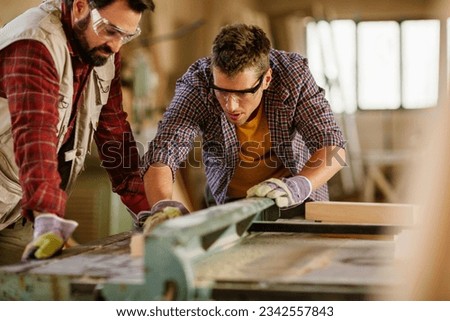 Two carpenters working together in a woodworking shop