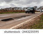 Two cars approaching a pot hole on a road on which the UK National Speed Limit for single carriage roads applies (60mph).