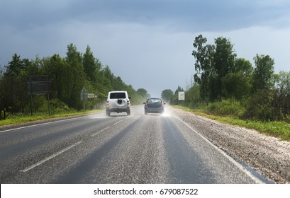 Two Cars Going On The Road After The Rain.