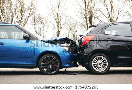 Two cars involved in traffic accident on side of the road with damage to bonnet and fender