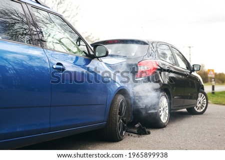 Two cars involved in traffic accident on side of the road with damage to bonnet and fender