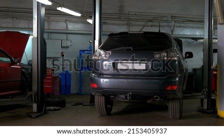 Two cars with an opened hood in car repair service. One car is lexus rx and another is Skoda Octavia. Back view of cars.