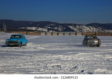 Two Cars Turquoise And Beige Pobeda On The Ice Snow Of The Hydroelectric Power Plant Reservoir