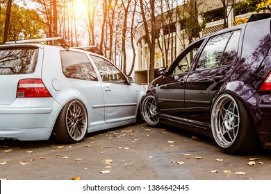 Two Cars White Blue And Purple Want To Take One Parking Space. Parking Problems In The City. Parked Tightly To Each Other. Snuggled Bumper. Low Tuned Cars With Forged Custom Wheels