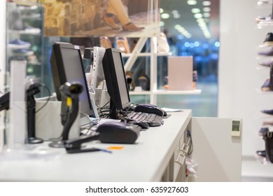 Two cash desks with computer screens and barcode scanners on white table and wall in small store
