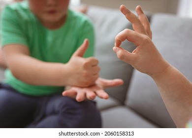 Two caucasian boys communicating using sign language while sitting on the couch at home. sign language learning concept - Powered by Shutterstock