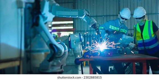 Two caucasian engineers male and female working control robotic arm welding with remote control. - Powered by Shutterstock