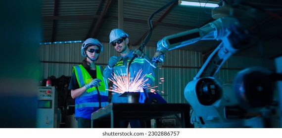 Two caucasian engineers male and female working control robotic arm welding with remote control. - Powered by Shutterstock