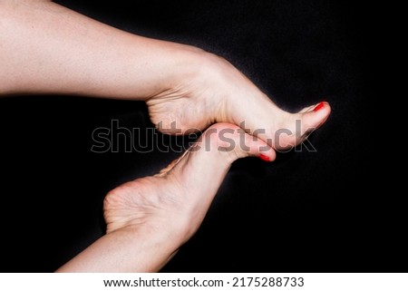 Two Caucasian female dancer's feet are touching each other isolated on black background