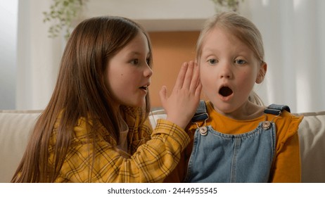 Two caucasian kids girls children sisters friends playing together at home older sister telling little girl news whispering in ear speak in whisper sharing secret gossip family relationship friendship - Powered by Shutterstock