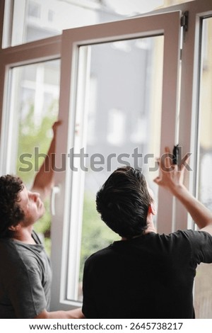 Two Caucasian men are installing window frames.