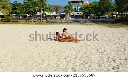 A two Caucasian pretty females in bikini laying and enjoying on a sandy beach, Koh Samui, Thailand